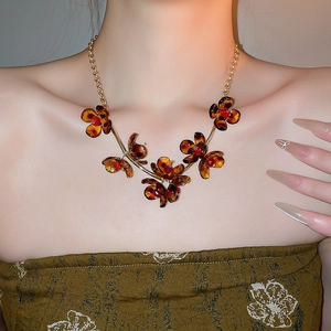 Close-up of amber flower petal necklace with red center on professional model