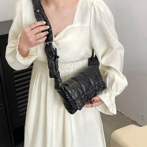 Detail of black quilted puffer crossbody bag with adjustable wide strap on model