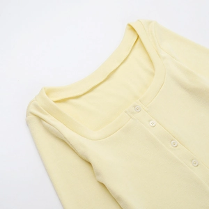 Dettaglio del cardigan in maglia a coste giallo chiaro con scollo a U e bottoni coordinati
