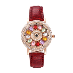 Luxury women's gold watch with red leather strap and rotating colorful floral rhinestone dial