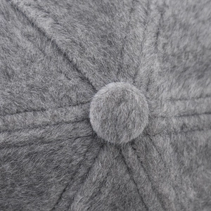 Vue détaillée du dessus d'un bonnet gris en peluche avec coutures et bouton central