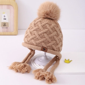 Detailed knit texture of children khaki earflap hat with faux fur pom pom and braided straps