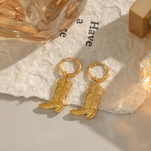 Detailed view of 18K gold plated stainless steel cowboy boot earrings on paper