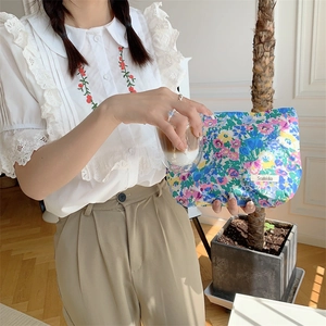 Detailed view of a floral cotton makeup bag held by a model in a lifestyle setting