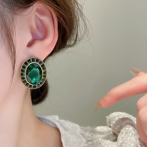 Boucles d'oreilles ovales vert émeraude rétro avec bordure dorée sur un mannequin