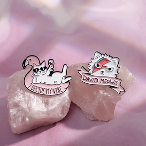 Cartoon enamel cat pins with David Bowie style and flamingo vibe on crystal stones