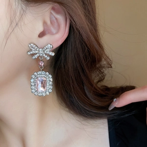 Gros plan de boucles d'oreilles nœud avec gemme rose rectangulaire et cristaux brillants