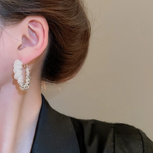 Close-up of minimalist silver hoop earring with beaded texture on a female model