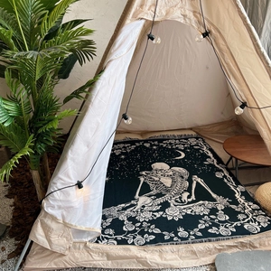 Detail of bohemian woven blanket with skull and rose pattern used in a cozy camping tent
