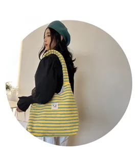 Close-up of yellow and blue striped plush tote bag with soft texture and wide strap