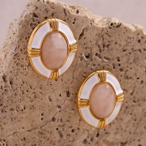 Detail of vintage 18K gold plated oval earrings with pink natural stone and white enamel