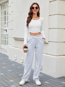 Top corto bianco da donna e pantaloni a zampa grigi a vita alta in un look all'aperto