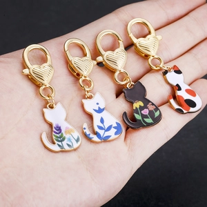Set of four colorful enamel cat back charms with golden heart lobster clasps on palm
