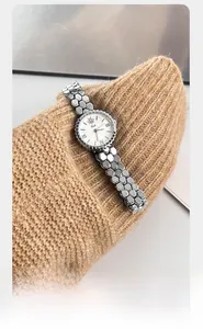 Detail of Gedi watch with honeycomb silver band and bee motif on a sweater cuff