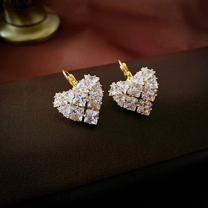 Macro shot of gold heart hoop earrings with shimmering cubic zirconia on leather