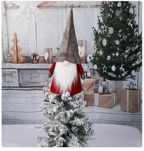 Détail macro d'un gnome de Noël nordique en feutre rouge et gris sur un sapin givré
