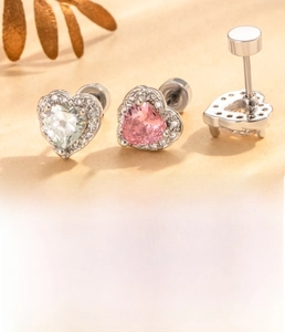 Detail view of heart-shaped zircon earrings with steel screw backs in pink and white