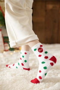 Close-up of white plush Christmas socks with red and green dots and JOY embroidery