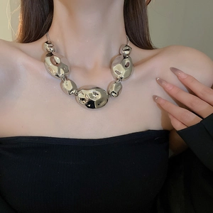 Fashionable silver necklace with bold pebble shaped links worn by a model in a close-up view