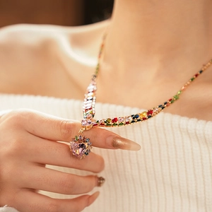 Detail view of heart-shaped pink gem pendant on gold necklace with colorful zircon stones