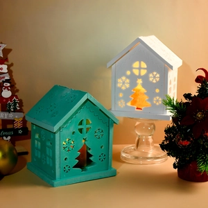 Close-up of wooden Christmas house candle holders with cutout snowflake and tree designs