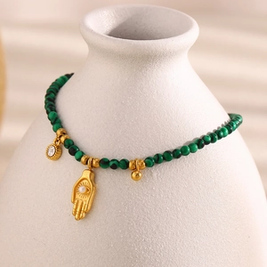 Macro detail of Hamsa charm and green turquoise beads on 18K gold plated bracelet