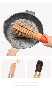 Detail of bamboo pot brush with ergonomic wooden handle cleaning a non-stick pan