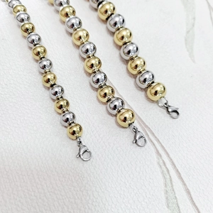 Close-up of dual-tone gold and silver beaded bracelets with lobster clasps
