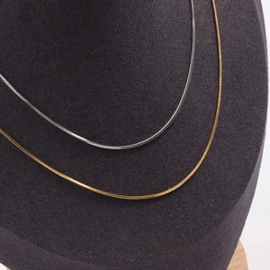 Elegant gold and silver square snake bone chain necklaces displayed on black stand