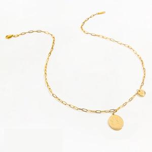 Detail of gold paperclip chain necklace with M letter charm and wheat oval pendant