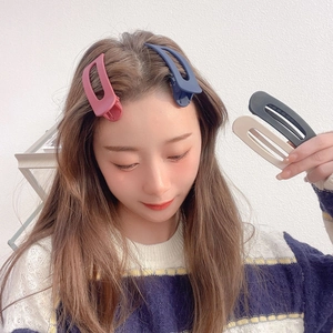 Close-up of matte resin hair clips in various colors shown on a model for side hair styling