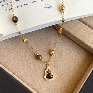 Detailed close-up of a gold 18K plated wulu pendant necklace with brown tiger eye stone