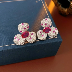 Detail of vintage flower earrings with pink and red gems on a blue jewelry box