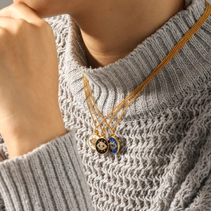 Three gold evil eye pendant necklaces with white, black, and blue zircon on a model