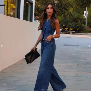 Detail of a dark blue denim set with sleeveless vest and wide leg pants in outdoor light