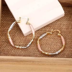Detail of chunky tricolor gold silver and rose gold textured hoop earrings on display