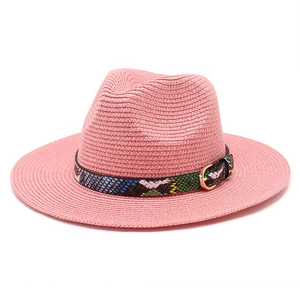 Close-up of pink straw fedora hat featuring a colorful snakeskin band and gold buckle