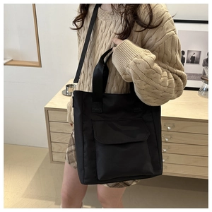 Detailed view of black large capacity tote bag with front pocket shown on model