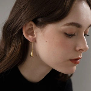 Close-up of elegant gold teardrop earrings with high-polish finish on female model
