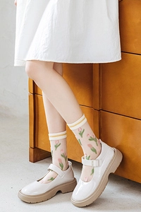 Détail de chaussettes beiges transparentes à motif tulipe avec chaussures Mary Jane