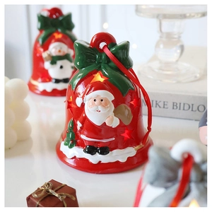 Detail of red ceramic Santa bell with LED star cutouts and festive green ribbon