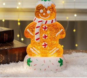 Close-up of glowing gingerbread man water globe with swirling glitter and warm light