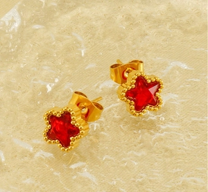 Close-up of star-shaped gold earrings with red zircon stones and beaded edges