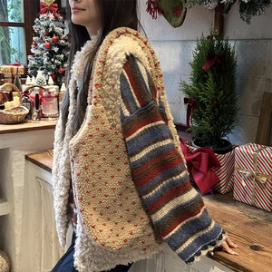 Détail du gilet et sac en laine d'agneau blanche à pois rouges sur fond de Noël festif