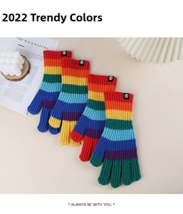 Macro view of four-pair set of rainbow striped knitted gloves with ribbed elastic cuffs