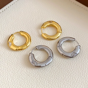 Detail of gold and silver hoop earrings with zircon inlay on textured leather background
