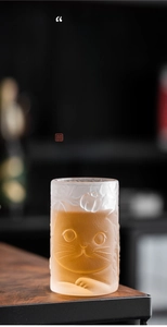 Macro detail of amber frosted glass cup featuring embossed 3D cat and persimmon patterns