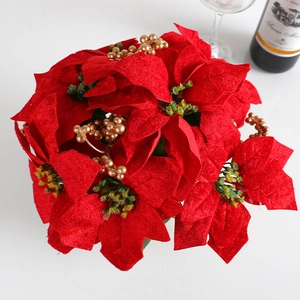 Potted red poinsettia Christmas flower arrangement with golden berries on table