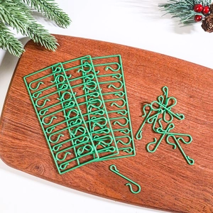 Close-up of green S-shaped Christmas tree ornament hooks on a festive wood background