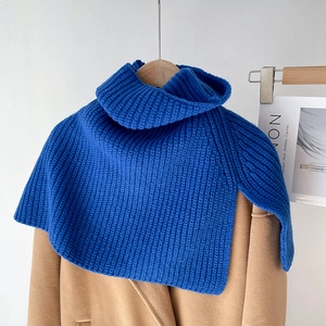 Detail of blue chunky knit turtleneck scarf with ribbed texture on camel wool coat